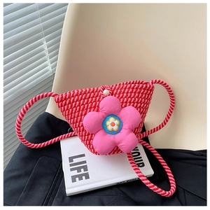 Detail der roten geflochtenen Tasche mit großer rosa Plüschblume auf weißem Stuhl