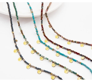 Detail of colorful stone beaded necklaces with small gold discs in Bohemian style