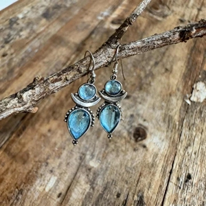 Detail view of retro bohemian earrings with blue resin moonstone on a rustic wood background
