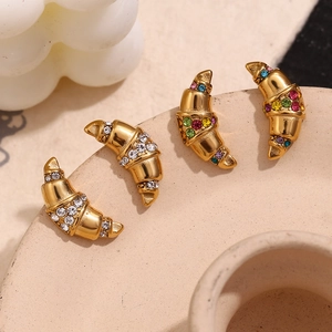 Detail of croissant-shaped gold earrings with colorful rhinestones on ceramic