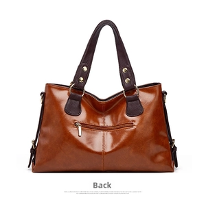 Detailed view of the brown leather shoulder bag featuring back zipper pocket and hardware rings.