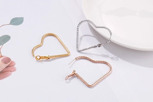 Détail des boucles d'oreilles créoles en forme de cœur en finitions or, argent et rose