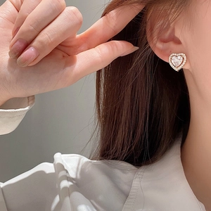 Elegant gold heart earrings with sparkling cubic zirconia crystals worn by a model