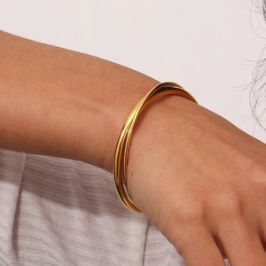 Close-up of a 18K gold plated stainless steel triple interlocked crossover bangle on a wrist