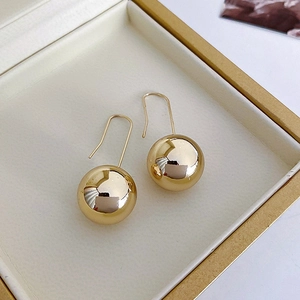 Detail of golden spherical earrings with long hooks inside a premium jewelry box