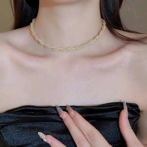 Close-up of a golden twisted rope chain necklace worn on a model with shimmering skin