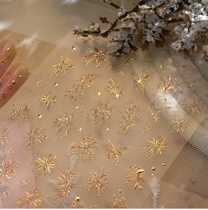 Macro shot of gold foil nail art stickers featuring fireworks and butterfly patterns