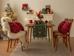 Detailed view of green Christmas table runner with festive patterns and gold tassels