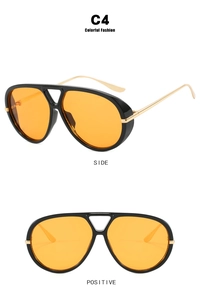 Detail of aviator sunglasses with orange lenses, black frames and gold metal temples