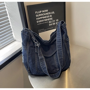 Détail d'un sac cabas en denim bleu avec bords effilochés sur table en métal