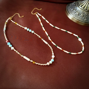 Detail of beaded necklaces with natural stones and colorful glass beads on a textured surface