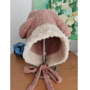 Dettaglio del cappello in maglia rosa e beige con orecchie da orso e cinturini