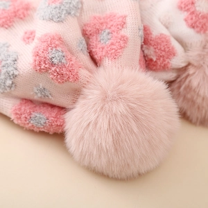Macro detail of winter knit hat featuring 3D floral embroidery and a soft fluffy pom-pom