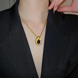 Elegant gold pear-shaped drop pendant necklace set with vintage red gems on model