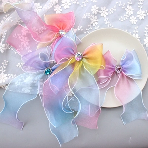 Rainbow gradient tulle bow hair clips with crystal center on a white lace background