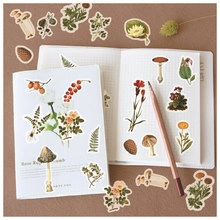 Close-up of vintage mushroom and flower stickers on a scrapbook page and table