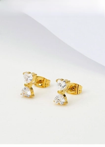 Detailed macro view of gold titanium steel bow earrings with sparkling heart-shaped zircons