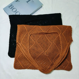 Detailed knit pattern of black and caramel crochet vests on a white fabric surface