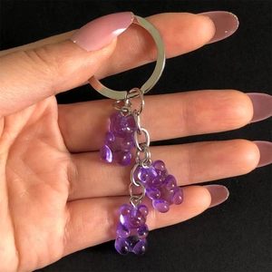 Handheld transparent purple gummy bear keychain with silver metal ring on black backdrop