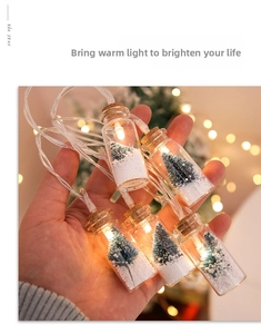 Macro shot of glass wishing bottles with miniature Christmas trees and warm LED lights