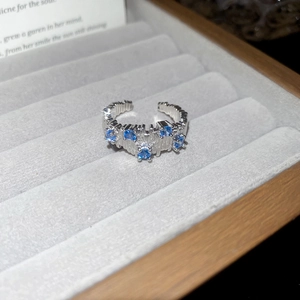 Detailed macro view of irregular silver textured ring with five blue zircons in a jewelry box
