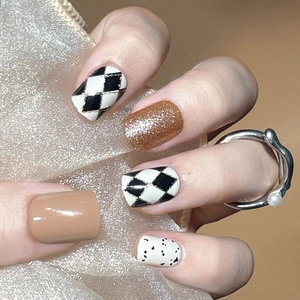 Press-on nails with checkerboard patterns, glitter and polka dots on elegant hands