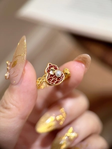 Detailaufnahme eines vergoldeten Flaschenkürbis-Rings mit Emaille und einer Perle