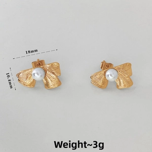 Detailed view of 18mm golden bow stud earrings with white pearls and textured finish