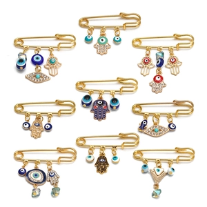 Set of 9 gold-tone safety pin brooches featuring Hamsa hand and blue evil eye charms