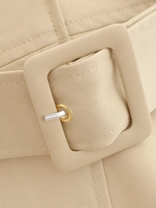 Gros plan sur la boucle de ceinture en sergé beige avec ardillon en métal doré