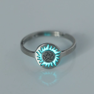 Detail of silver stainless steel ring featuring blue glowing star and flame patterns