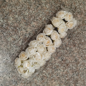 Macro view of ivory artificial rose flower heads in clear plastic packaging