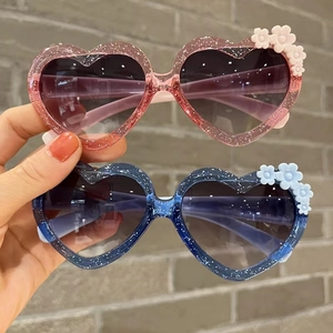 Detail of glitter heart sunglasses for kids featuring 3D flower accents and gradient lenses
