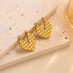 Vue macro des boucles d'oreilles cœur dorées 18k avec texture en relief 3D
