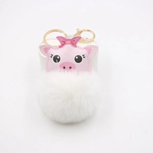 Detail of pink leather pig head and white fluffy pom pom on a golden metal keychain