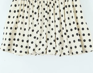 Detailaufnahme des cremefarbenen Stoffes mit schwarzem Punktmuster und elegantem Faltenwurf