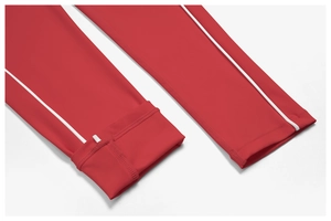 Detail of red yoga jumpsuit featuring precise white piping and reinforced ankle cuffs