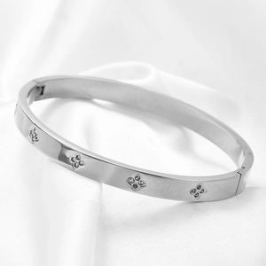 Macro-opname van zilveren stalen armband met diamanten klavertjes op witte zijde