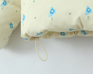 Detail of light yellow jacket hem featuring blue print and metal drawstring toggle