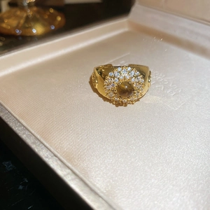 Macro view of wide gold plated ring with tiger eye stone and crystal halo details