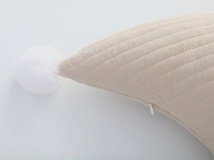 Detail of quilted cotton nursing pillow with white pom poms and hidden zipper closure