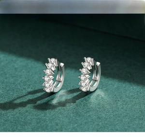 Macro detail of silver hoop earrings with five sparkling cubic zirconia on green surface