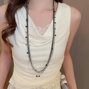 Elegant multi-layer beaded necklace featuring silver chains and black beads on a model