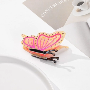 Detailed shot of an amber acetate butterfly hair claw with pink rhinestones and a black clip