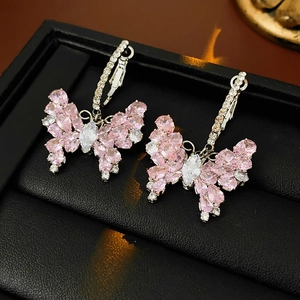Macro shot of pink zircon butterfly earrings on black jewelry box with warm lighting