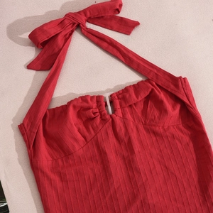 Dettaglio del top rosso allacciato al collo con trama a costine e fiocco decorativo