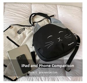 Detail of cute black cat canvas bag showing size comparison with iPad and phone