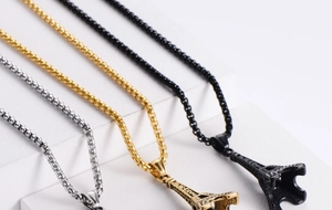 Macro view of Eiffel Tower pendants in silver, gold, and black with France engraving