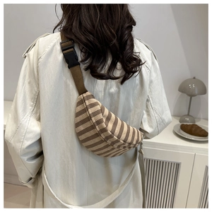 Detail of striped corduroy chest bag featuring brown adjustable strap and buckle closure