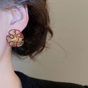 Detailed view of flower-shaped red enamel earrings with gold-plated hollow lines